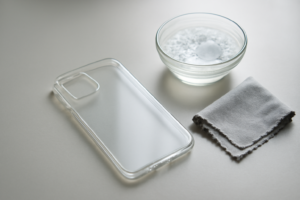 Case HP bening yang sedang dibersihkan dengan kain mikrofiber di atas meja
